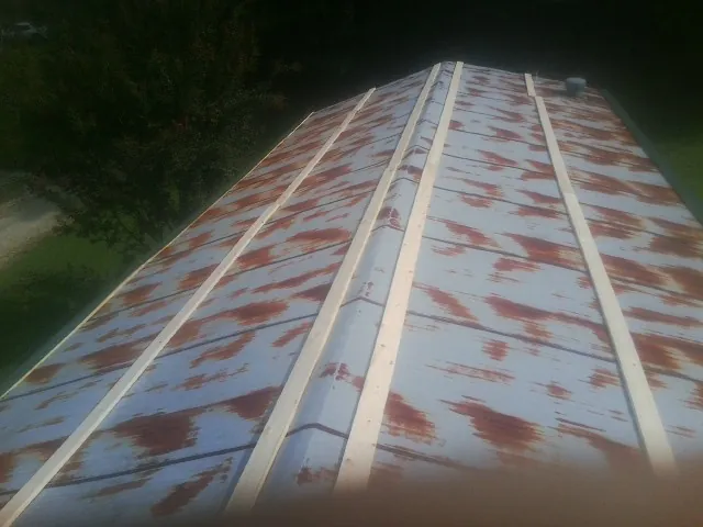 Rusted metal roof panels with new wood purlins before replacement — Storm Damage Roof Repair in Knowlesville by Roofing Brothers