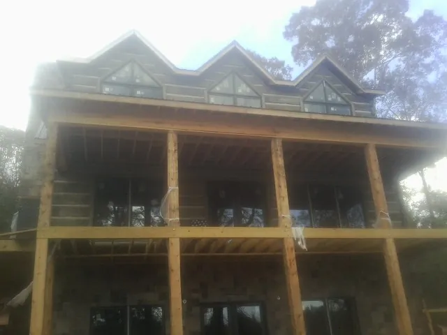 Dormers and porch framing on a large log home under construction — Roof Coating work by our crew in Knowlesville