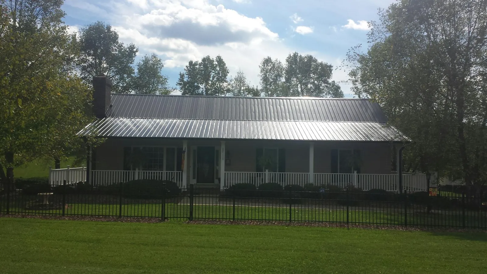 Gray metal roof on a brick ranch with a full width front porch — Gutter Guard Installation work by our crew in Knowlesville