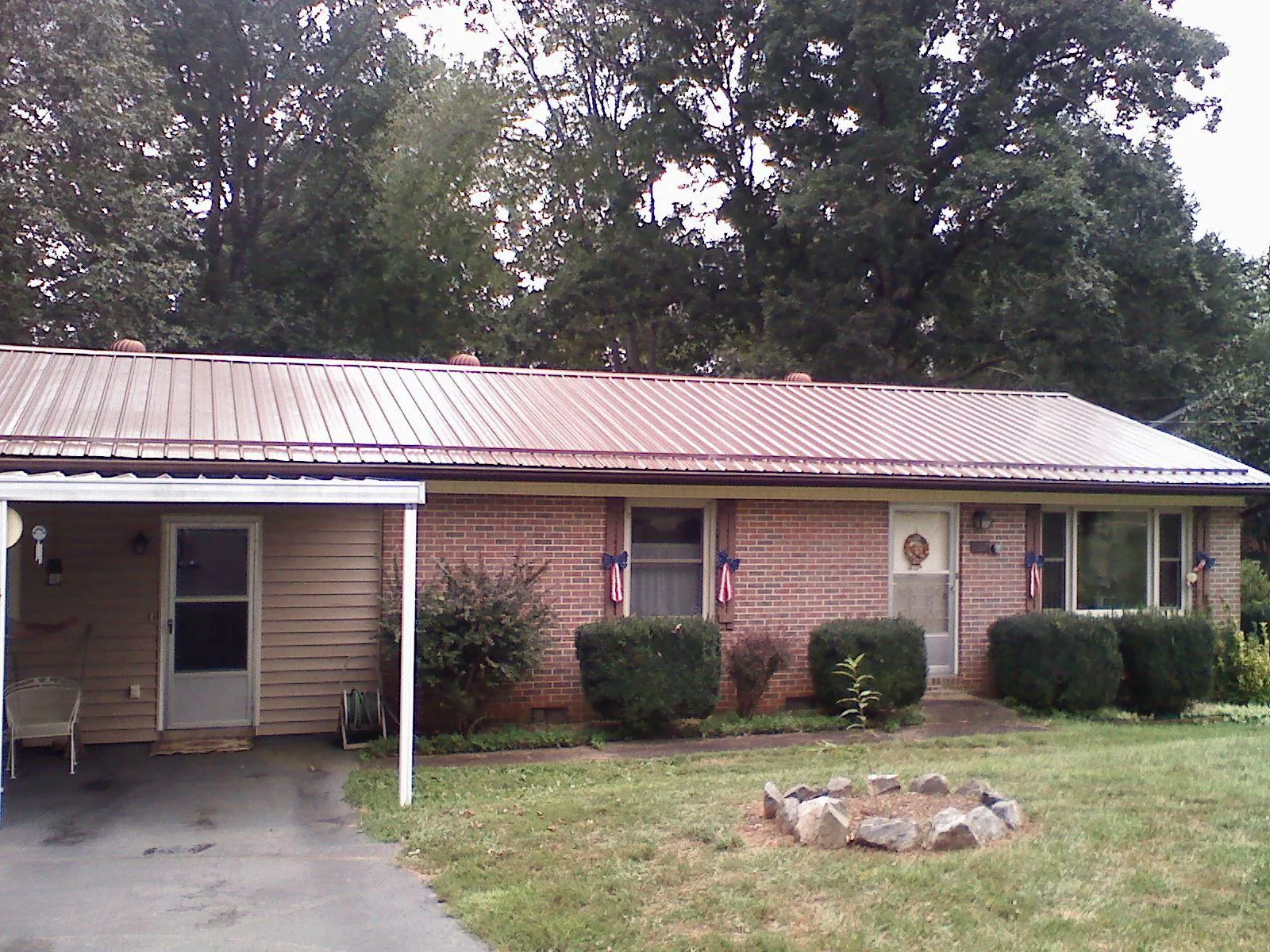 Bronze metal roof and carport on a brick ranch home — Roof Repair work by our crew in Knowlesville