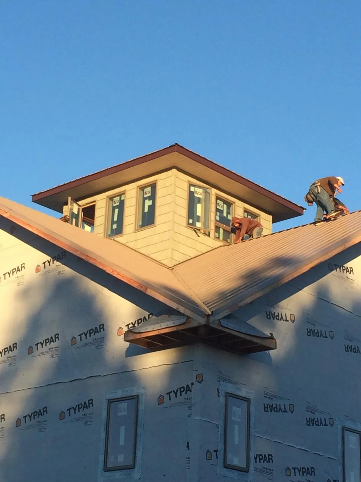 Roofers working around a rooftop cupola on a new metal roof at sunset — Roof Waterproofing in Knowlesville by Roofing Brothers